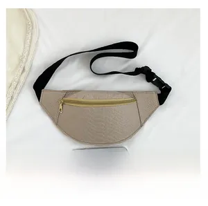Detail of khaki crocodile pattern chest bag with gold zipper and size comparison phone