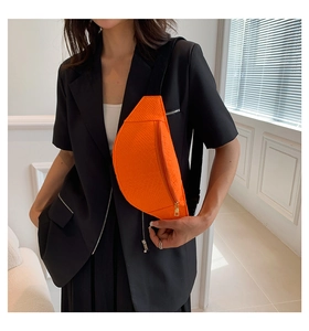 Close-up of vibrant orange crescent chest bag with animal skin texture and golden zipper