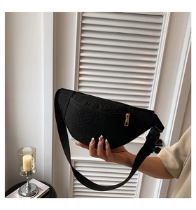 Detail of black crocodile texture chest bag with golden zipper and nylon strap