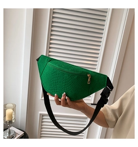 Detail of green crocodile texture chest bag with gold zipper and adjustable strap