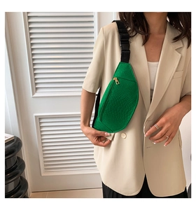 Detail of emerald green crocodile pattern chest bag with gold zipper and nylon strap