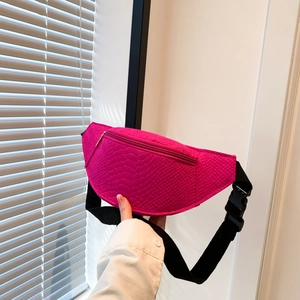 Detail of pink snakeskin texture on a crossbody bag with black adjustable strap and buckle