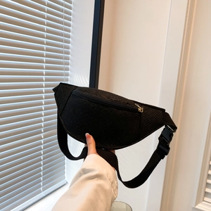 Detailed view of black nylon chest bag with golden metal zipper and plastic buckle strap