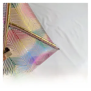 Detail aus holografischem Wellenstoff und goldener Metallic-Lederkante an der Modetasche