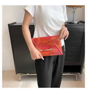 Details der orange-roten Briefumschlag-Clutch mit Fischgrätmuster und Goldverzierung