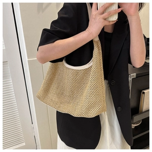Close-up of beige woven summer tote bag with white leather trim on a female model