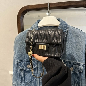Close-up of black quilted bag featuring gold twist lock and metallic ball chain detail