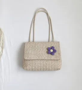 Detailed close-up of woven straw handbag with purple knitted flower decoration