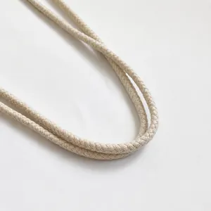 Detailed macro view of the cream woven cotton rope handle on a stylish straw bag