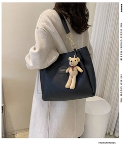 Chic black PU leather tote with gold chain strap and bear charm on model's shoulder