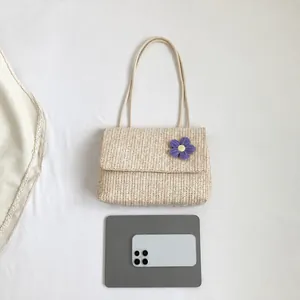 Straw shoulder bag with purple floral detail shown next to a tablet for size reference