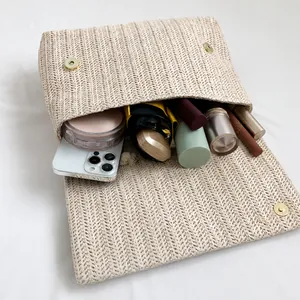 Interior detail of a straw clutch bag showing capacity for phone, cosmetics, and umbrella