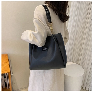 Detail of black tote bag with gold chain strap and fashion label on leather texture
