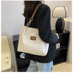 Detailed side view of white PU tote bag with gold chain and brown leather straps