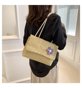 Dettaglio borsa a tracolla in paglia intrecciata con fiore viola e manici in corda