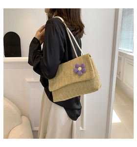 Dettaglio della borsa a tracolla in paglia beige chiaro con texture intrecciata e fiori