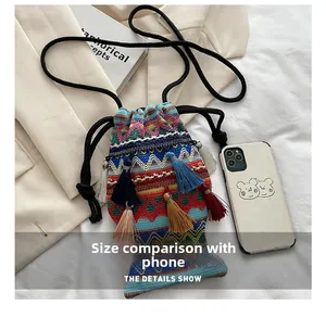 Details einer gewebten Fisch-Tasche mit Fransen neben einem Handy zum Größenvergleich
