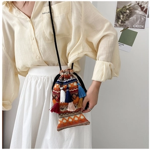 Detailansicht der fischförmigen Stricktasche mit bunten Quasten und Textur