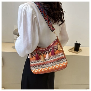 Detail of bohemian woven shoulder bag with vibrant tassels and embroidered wide strap