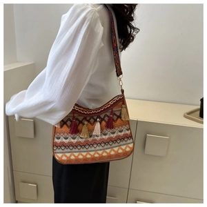 Close-up of bohemian jacquard woven shoulder bag with colorful tassels and wide ethnic strap