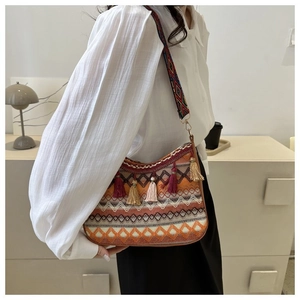 Detail of bohemian crossbody bag with geometric patterns, fringe, and a wide woven strap