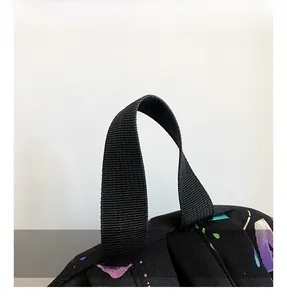 Detail view of the durable nylon top handle on a black printed backpack for students