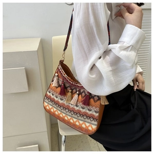 Close-up of ethnic style woven crossbody bag with colorful tassels and wide patterned strap