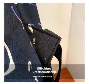 Macro shot of reinforced stitching craftsmanship on a black backpack with colorful ink splashes