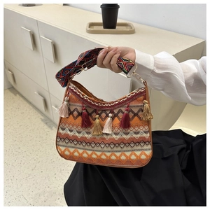 Detail of ethnic woven shoulder bag with colorful tassels and patterned wide strap