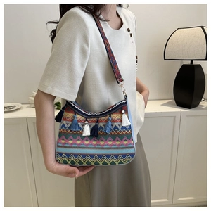 Detail of ethnic crossbody bag featuring colorful jacquard patterns and blue fringe tassels