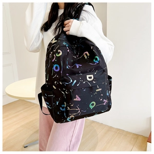 Detail of black backpack showing colorful metallic letter prints and inkjet patterns