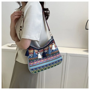 Detail of bohemian knit shoulder bag with colorful wave patterns and long tassel fringe