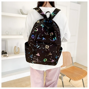 Detail of black backpack featuring colorful holographic letters and artistic ink splash patterns