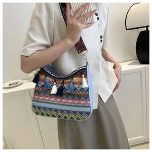 Close-up of ethnic bohemian shoulder bag with colorful tassels and geometric strap