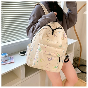 Close-up of beige backpack featuring holographic letters and colorful splatter patterns