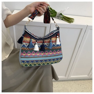 Detail of bohemian woven bag featuring colorful tassels and embroidered ethnic wide strap