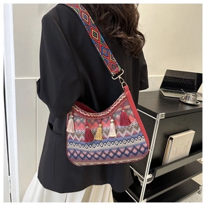 Detailed close-up of a colorful ethnic style bag with long tassels and embroidered strap