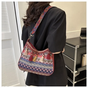 Detail of bohemian woven shoulder bag with colorful fringe tassels and a wide jacquard strap