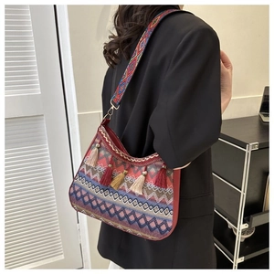 Detailed view of bohemian woven crossbody bag with colorful tassels and wide shoulder strap