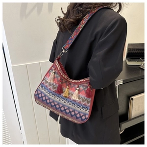 Detail of bohemian red geometric tapestry bag with colorful tassels and wide strap