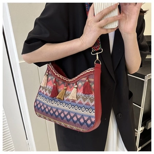 Close-up of ethnic bohemian crossbody bag featuring red fringe and colorful woven shoulder strap