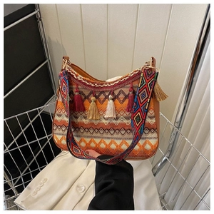 Close-up of bohemian woven crossbody bag with colorful tassels and wide patterned strap