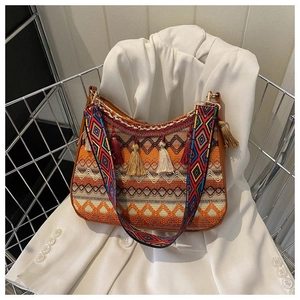 Detail of bohemian woven bag with vibrant tassels and wide geometric patterned shoulder strap