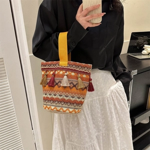 Dettaglio della borsa a secchiello boho con motivi geometrici arancioni e nappe colorate