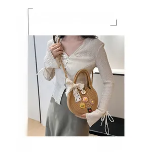 Détail du sac en paille rond avec accents floraux et nœud en dentelle délicat
