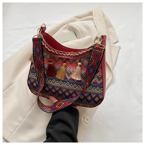 Detail of ethnic woven bag with colorful tassels and wide shoulder strap on blazer