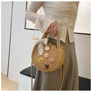Détail du sac rond en paille tressée avec fleurs 3D faites main et nœud en dentelle