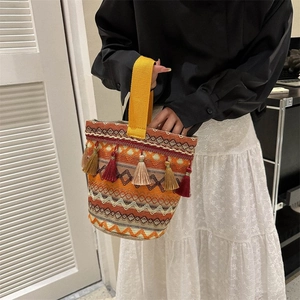 Dettaglio di borsa tessuta boho con nappe colorate e un vivace manico giallo acceso