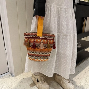 Dettaglio borsa a secchiello etnica intrecciata con motivi geometrici e nappe decorative