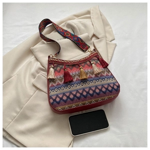 Detail of bohemian crossbody bag with woven geometric patterns and colorful tassels